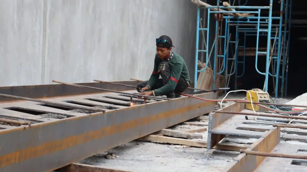 Pekerja konstruksi melakukan pengelasan pada struktur besi